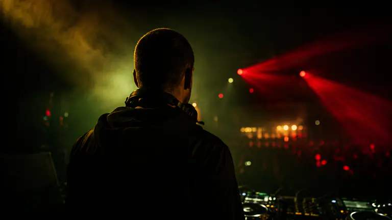 Deejay Tin'Ok atrás dos pratos - público iluminado em tons quentes numa noite de clube em Londres